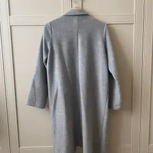 Tunnare grå kappa från H&M. Rak modell. Knälång.   Storlek 32. Jag har oftast storlek 34 men kan även ha denna jacka.  