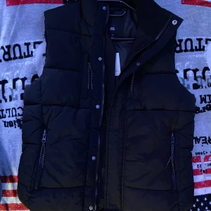 River Island Puffer Väst - En svart River Island väst. Aldrig användt. den är helt ny köpte för några månader sedan. Pris kan sänkas. Nypris: 45£