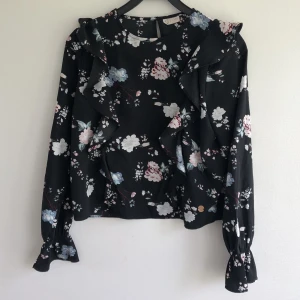 Blommig blus - Säljer nu denna fina blommiga blus med volanger på. Sparsamt använd, därav mycket fint skick helt utan defekter. Säljes nu på grund av brist på användning. Storlek 170, passar ca S. Rensar bland kläderna så kolla gärna mina andra annonser också🥰