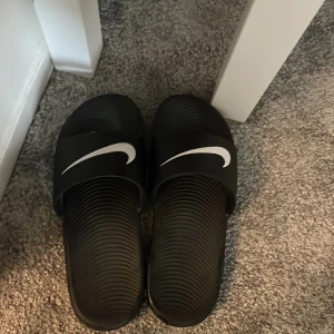 Nike tofflor - Säljer svarta Nike tofflor eftersom att jag råkade köpa dom i fel storlek och tagit av lappen redan.  Dom är ej använda, pris kan diskuteras vid snabb försäljning.