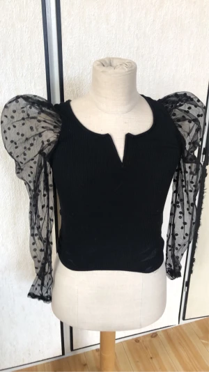 Svart blus - Jätte fin svart tröja med puffärmar med prickar på, jätte fin och varsamt använd, perfekt för svala sommarkvällen eller en vild utekväll. Sjukt snygg och har även en v-ringning.
