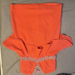 Koral klänning med pärlor  - En jätte fin koral färgad klänning med flera olika pärlor på. Den är knappt använd och därför har inga defekter och är som i ett nyttskick. Den ser lite orange ut på bilden men lutar mer åt rosa i verkligheten. 