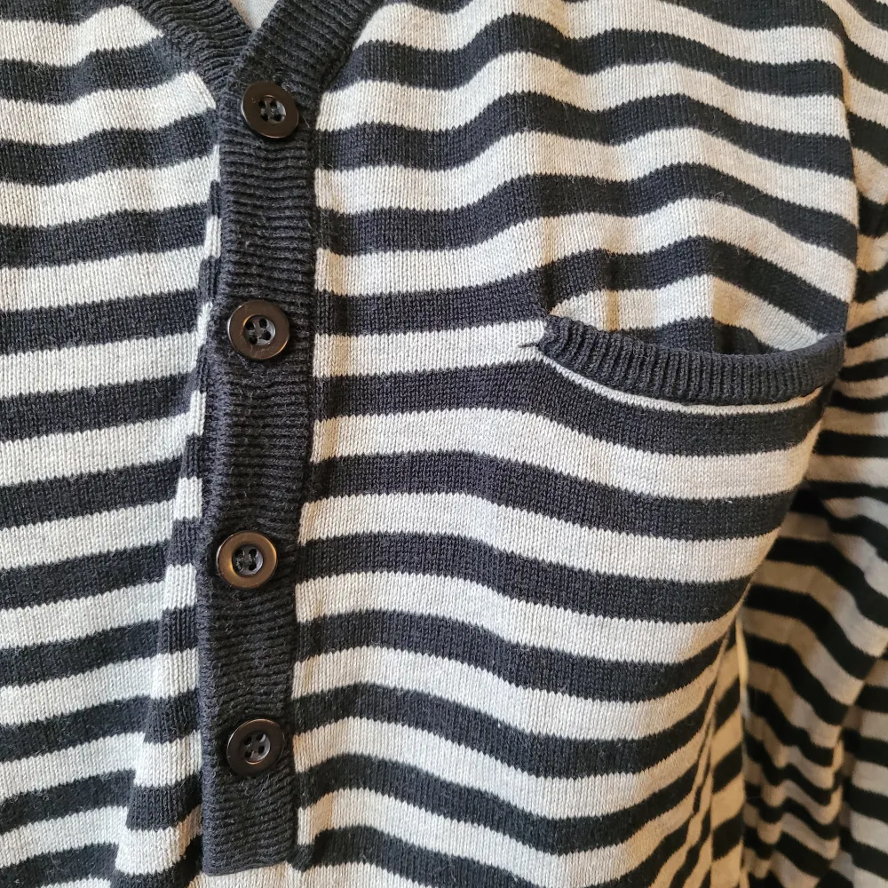 Randig v-ringad grå och svart långärmad tröja med en bröstficka, knappar och detaljer på axlarna.. Tröjor & Koftor.