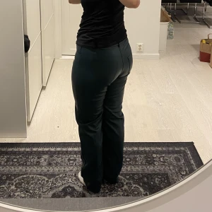 Mörkgrön PU-byxa - Ett par raka mörkgröna PU-byxor från GinaTricot. Knappt använda men har ett litet rivmärke på ena benet (tror det var så när jag köpte dom), men det syns knappt! Ganska höga i midjan.