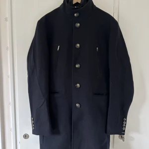 Ullrock från J.Lindeberg  - Ullrock från J.Lindeberg med avtagbar väst fodrad i återvunnen ullmelton. Västen kan även användas separat. Sparsamt använd, bilderna ger inte rocken ett ärligt intryck.  Nypris: 5900:-  Storlek:46 