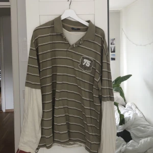 Grön/vit t-shirt tröja  - Grön randig t-shirt som sitter ihop med en gräs vit tröja med tryck på ryggen  Köpt secondhand men bra skick  Köpt för 150kr Säljer för 70kr