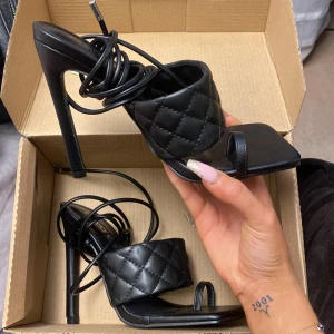 Höga klackar öppen tå med snöre strlk 37 - Super snygga 12 cm högklackat med öppen tå! Snöre som snurras upp till benen. Aldrig använda, som nya. Extra klackskydd som medföljer i dens egna sko låda. 