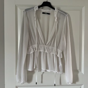 Blus - En vit tunn blus från bikbok med v- ringad hals och knytband.
