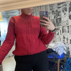 Röd pullover med dragkedja som är thriftad