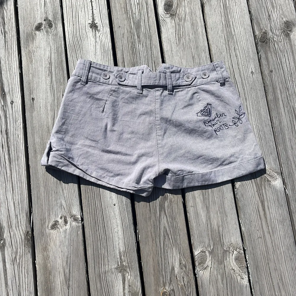 Blå randiga lågmidjade sommarshorts med broderi POXY på framsidan och ”Remember your Roots” på baksidan. Shortsen är justerbara i midjan. Säljer då de är en aning för små för mig.. Shorts.