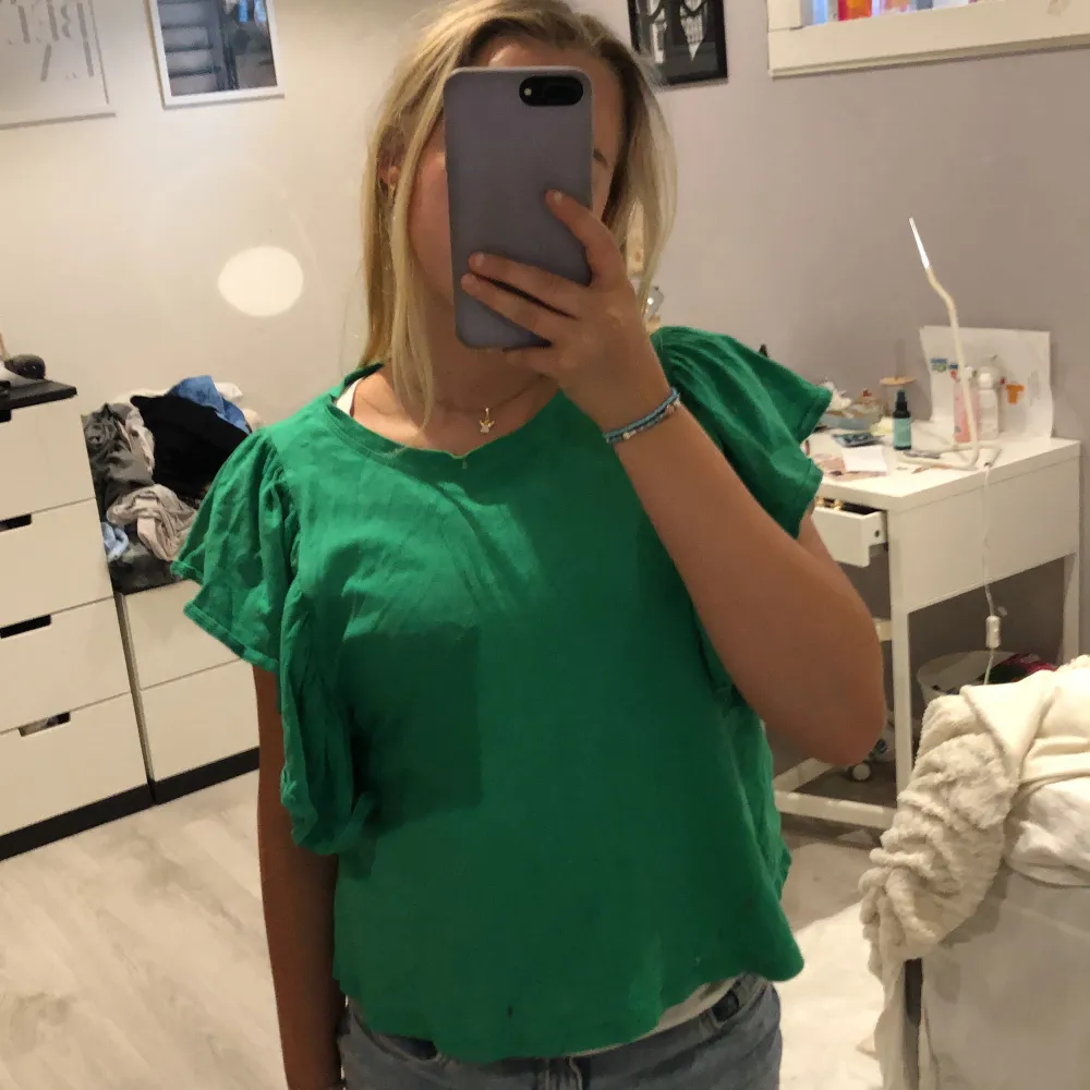 En jättefin grön tröja med volanger från Zara, Tröjan är slutsåld. Har nästan aldrig använts. Tröjan har inga hål eller fläckar💓. T-shirts.