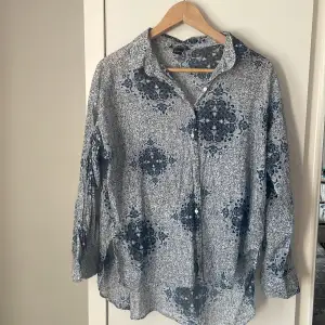 Superfin skjorta i 100% bomull med ett fint blått mönster. Den är något längre bak än fram