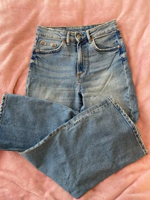 Högmidjade jeans från h&m strl 25 - Jättefina högmidjade jeans strl 25. Stretch, vida ben men inte jätte. Jättefin tvätt, slitningarna är original.  Innerbenslängd 67 cm, midjan rakt över 32 cm. 