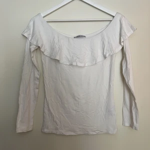 Off shoulder topp med volang  - Tight, mjuk och tunn långärmad off shoulder tröja i bomull med en söt volang.