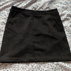 Mockakjol mini - Svart mockakjol från Vero Moda med två fickor på var sin sida, stl S går till mitten på låret!