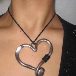 Stort hjärthalsband  - Halsband med stort assymetrisk metall hjärta  I bra använt skick   Längd enligt bild 