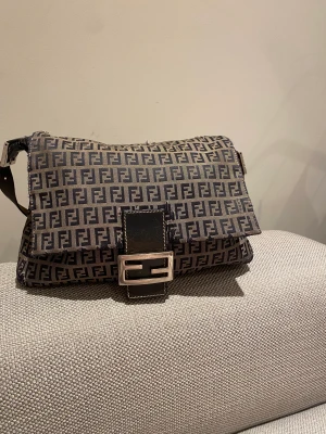Fendi väska - Säljer min Fendi väska då den inte kommer till användning längre. Köpt på TheVintageBar.  Använt skick.  Bara att höra av sig för fler bilder! Äkthetsbevis och kvitto finns!  Modell: Navy Fendi Canvas Baguette 