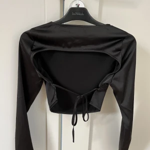 Svart satintopp med öppen rygg🫶🏼 - Säljer denna otroligt snygga satintoppen med öppen rygg från missguided❤️‍🔥den är köpt för ca 2 år sedan men använd endast 2 gånger! Säljer då den ej använda längre (andra bilden är lånad)