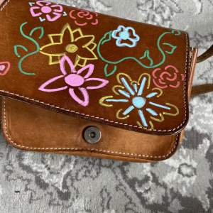 Super fin liten handväska i läder i väldigt gott skick. Har ett fantastiskt litet blommönster i olika färger påmålat. 