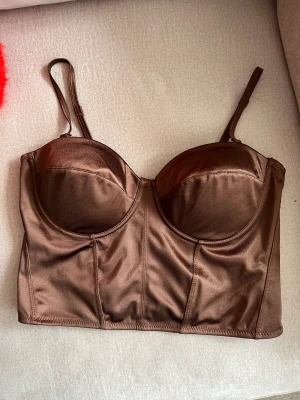 Topp/bralette  - Helt ny med lappar kvar. Storlek L men är liten. Brun och har justerbara axelband. 60kr plus frakt