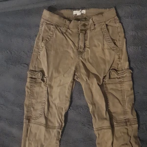 Grön/bruna cargo byxor - Ett par snygga gröna bruna cargo byxor som e köpta på H&M, säljer 💕dom eftersom dom har blivit alldelles för korta, tror dom skulle passa 160-165 väldligt bra💕