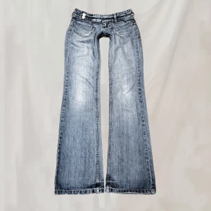 Lågmidjade jeans - Midja:74 innerben:83 Lågmidjade jeans. Uppskattar till en XS/S. Slitningar enligt bild, skulle dock säga att de även är del av designen. Nötta partier, samt hål vid bakre fotändarna. Missade stoppa in bandet i ena ögglan på första bilden🤍