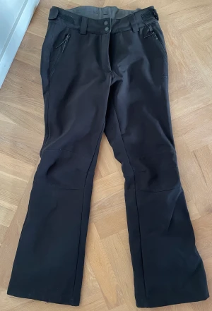 Skidbyxor/täckbyxor  - Skidbyxor/täckbyxor för dam, ganska smal modell. Dragkedja längst nere för pjäxorna. Fint skick