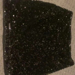 Tajt kort glitter kjol  - En jätte fin tajt, kort och glittrig svart kjol som är ifrån H&M. Den har även en dragkedja vid sidan om. Den är i ett perfekt skick och är som ny. Använd få tals gånger. 
