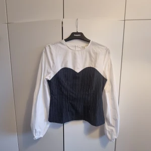 Skjorta/blus med korsett H&M - Skjorta/blus med korsett detalj i randigt marinblått. Stora ärmar. Från H&M storlek 38