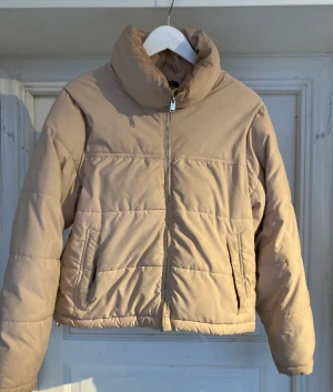 Dunjacka GinaTricot ljus beige small - Lätt beige dunjacka från GinaTricot i storlek Small. Den har vissa missfärgningar från smink vid kragen och är lite mörkare vid fickorna.