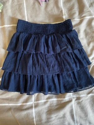 Volangkjol från Lindex - Marinblå volangkjol från Lindex barnavdelning i storlek 122/128. Sitter perfekt på mig som är 162 cm. Skriv för mer bilder
