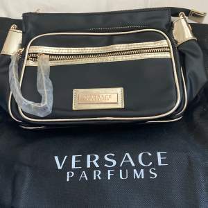 Väskan är i märket Versace parfums i färgen svart den köptes för några dagar den och är helt oanvänd, väskan är i bästa skick och köpte den för ca 700kr men säljer den för 250! (Frakt ingår ej) 