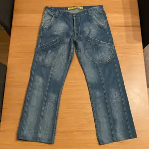 Ett snyggt par jeans med tydliga sömmar och extra fickor vid låren. En snygg wash kombinerat med detaljer som extra ”hemming” och slutligen unika bakfickor gör dessa schyssta. Ingen sizing, men stora Längd 94cm Midja 43x2 Skriv om det finns frågor :)  