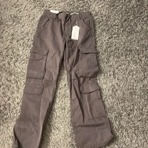 Cargobyxor - Mörkgrå cargobyxor från bershka som aldrig använts, storlek 38. Finns snöre i midjan som man kan justera själv. 