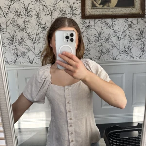 Topp med puffärm  - En beige topp från H&M med puffärm samt knappar i linne material.