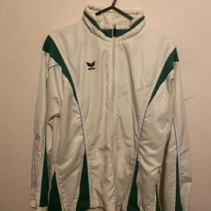 Erima träningsjacka - Den är i bra skick men har använts ett par gånger och har ett märke men kan lätt gå bort.  Ljuset är lite konstigt i bilderna men den är vit