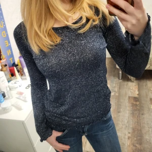 Glittrig festtröja blå - Köpt secondhand och väldigt älskad, men har nu bytt stil. Superbra kvalitet och bra skick, helt perfekt tröja. Mysig, sticker inte. Ser så bra ut med blixt då den är stickad med silvrig mettalisk tråd. Går ut i ärmarna. Liiite genomskinlig.