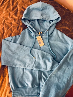 Blå hoodie - Supersnygg, helt ny hoodie från NA-KD. Storlek Xs