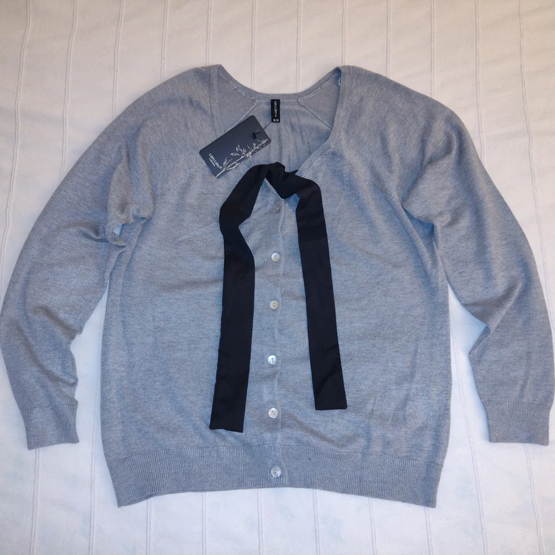 Oanvänd! Gråmelerad finstickad kofta med svart knytband och pärlemorfärgade knappar, storlek S (36/38)