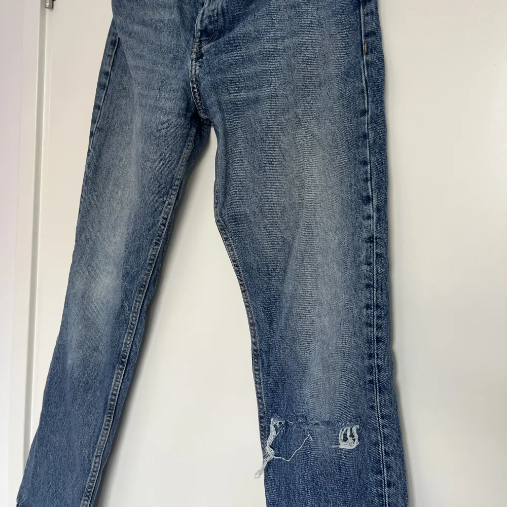 Säljer dessa supersnygga zara jeans som har blivit för små för mig.  Midwaist och straight modell som inte går att köpa längre, så fin blå färg! De har en slitning på ett av benen vid knät (tredje bilden) vilket gör dem lite mer unika!. Jeans & Byxor.