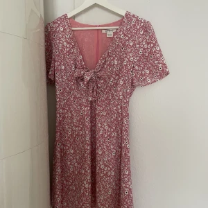 Blommig klänning  - Klänning med knut vid bröstet. Man knyter själv.  Använd fåtal gånger 