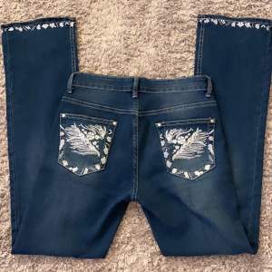 Low waist bootcut jeans med coola broderier! Midjemåttet: 36cm (tvärs över) Innerbenslängd: 79cm. Byxorna är stretchiga så passar även större storlek. Använda fåtal gånger. Använd gärna köp nu! Bara o skriva vid fler bilder eller frågor💘