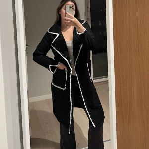 Svart kappa - Svart kappa som aldrig har används!! Jag önskade en lite längre kappa, men den har väldigt fina detaljer. Det ingår även ett svart band med samma vita detaljer på. Passar S. Nypris 1200