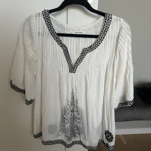 Blus  - Vit blus med fina detaljer vid ärmarna magen och längst ner på blusen. Blusen är väldigt luftig och är aldrig använd 