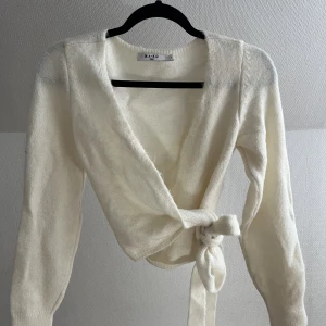 Stickad tröja - Krämvit stickad tröja i omlottmodell. Använd endast ett fåtal gånger. 