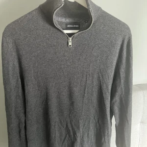 Half zip tröja - Tunnstickad halv zip tröja från Jack & Jones i mörk grå färg, storlek S. Knappast använd så i väldigt bra skick! Säljer pga för liten. Nypris 400! Hör av er vid frågor eller intresse!