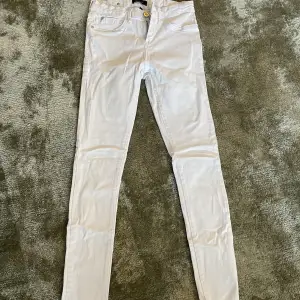 Tighta vita jeans. Ej genomskinliga. Små i storleken. 34-36 skulle jag uppskatta dem till.