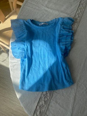 Blått Zara linne - Blått linne med volanger från Zara i S men passar XS. Har använts 3-4 gånger och är i nyskick.