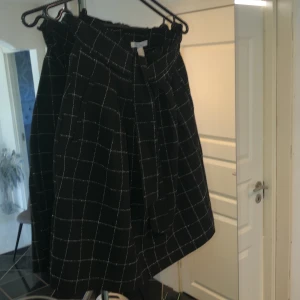 Kjol - Svart och vit randig kjol med knytning runt midjan och dragkedja baktill. 