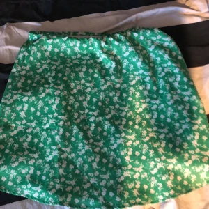 Grön kjol  - Grön kjol med vita blommor, nästan aldrig använd. Billigt pris för använder aldrig